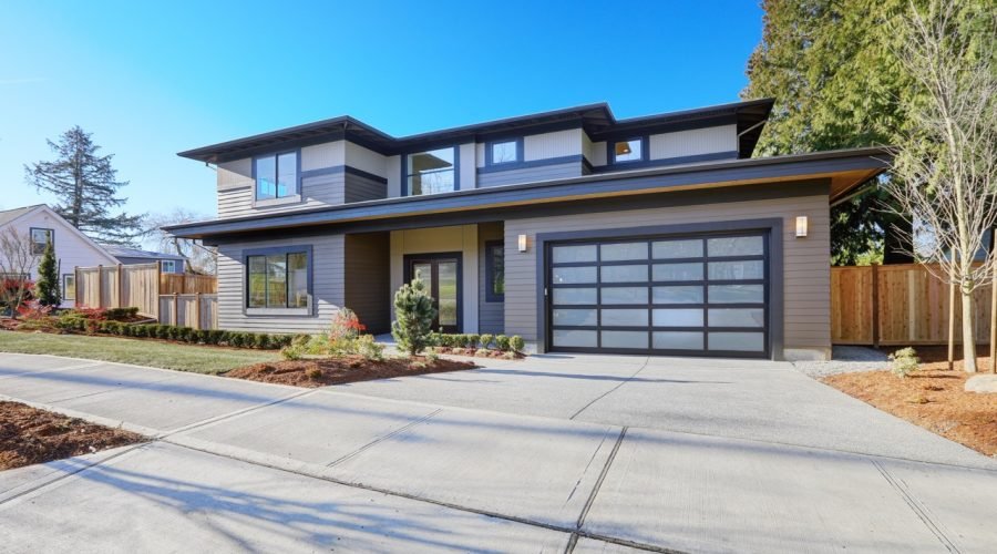 New construction home exterior with contemporary house plan  features low slope roof, brown siding and glass garage door. Northwest, USA